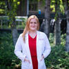 Angela Rocchi, MD/PhD student, is standing on campus in her white coat and red scrubs.