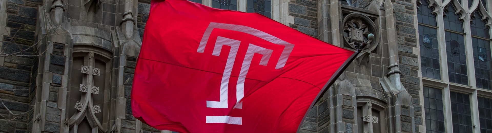 The Temple T flag raised in front of Mitten Hall. 