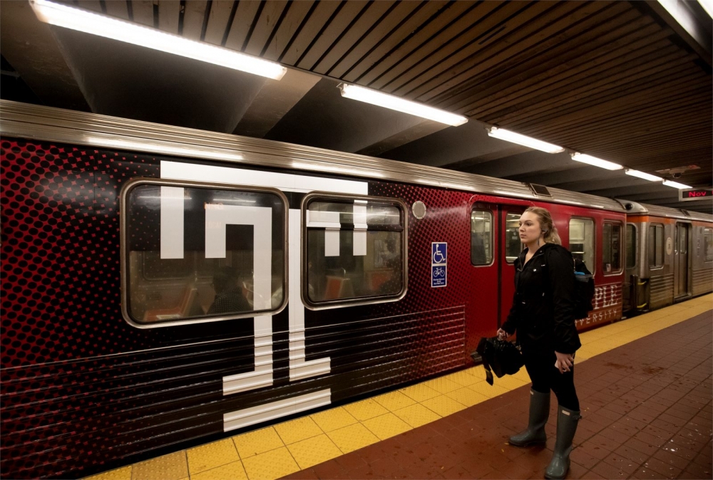 Woman standing in front of a subway car with a Temple University logo on it.
