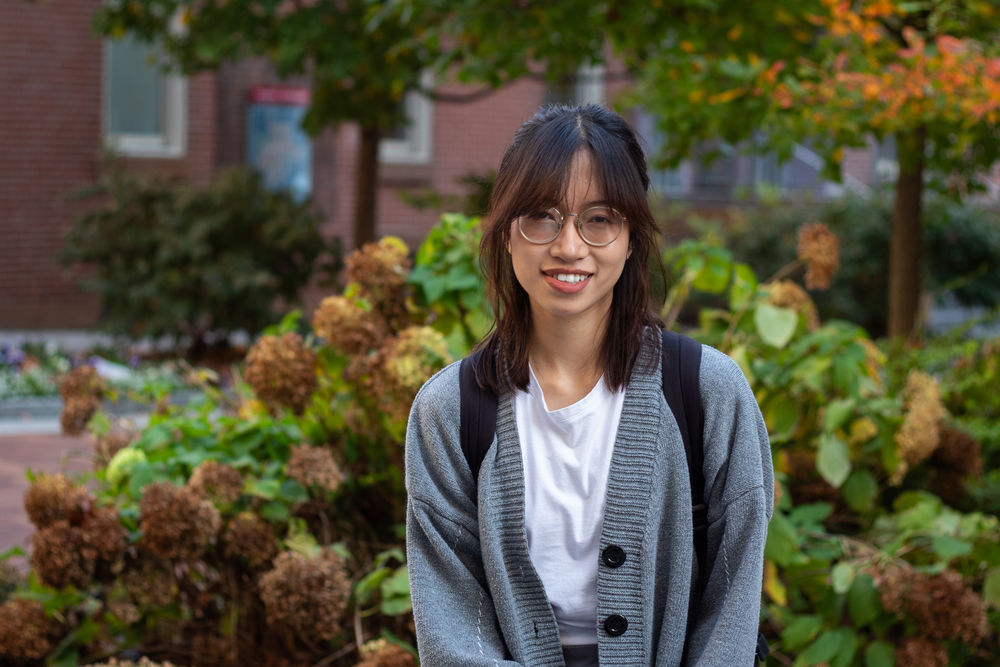 Masters student Linh Vo stands smiling on campus
